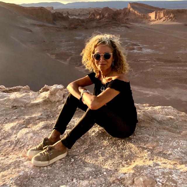 Fora travel agent Susanna Townsend sits on rock with mountains in background