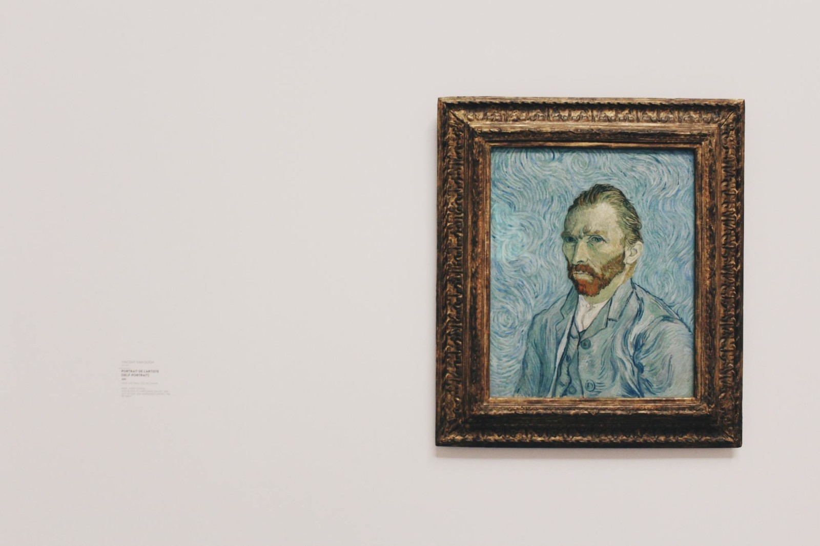 Van Gogh self-portrait against white wall in museum. 