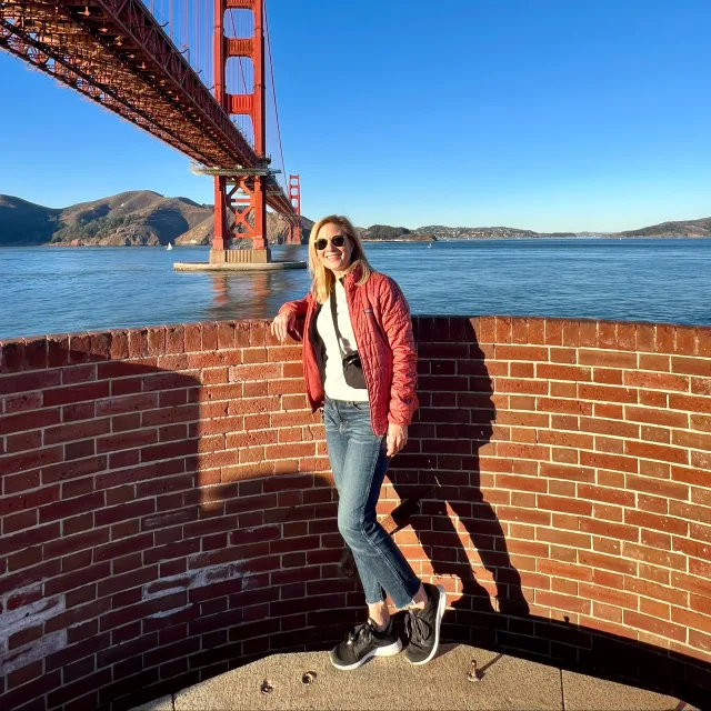 Picture of Kristy wearing a red jacket, white top and jeans at Fort Point National Historic Site
