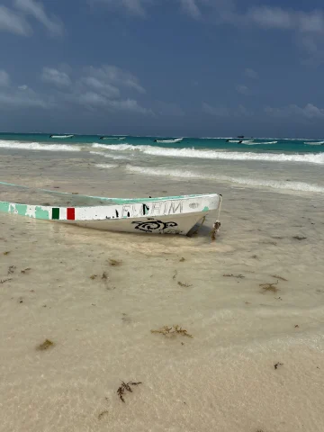 A boat half-buried in the sand on the beach during the daytime