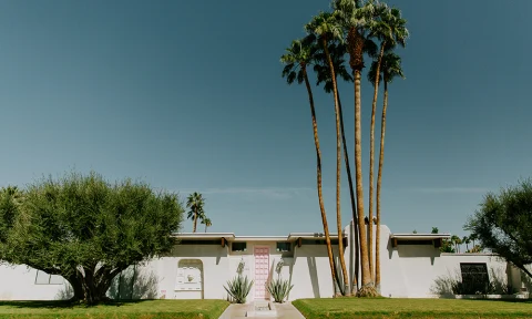 A white Spanish-style home with a pink front door in Palm Springs.