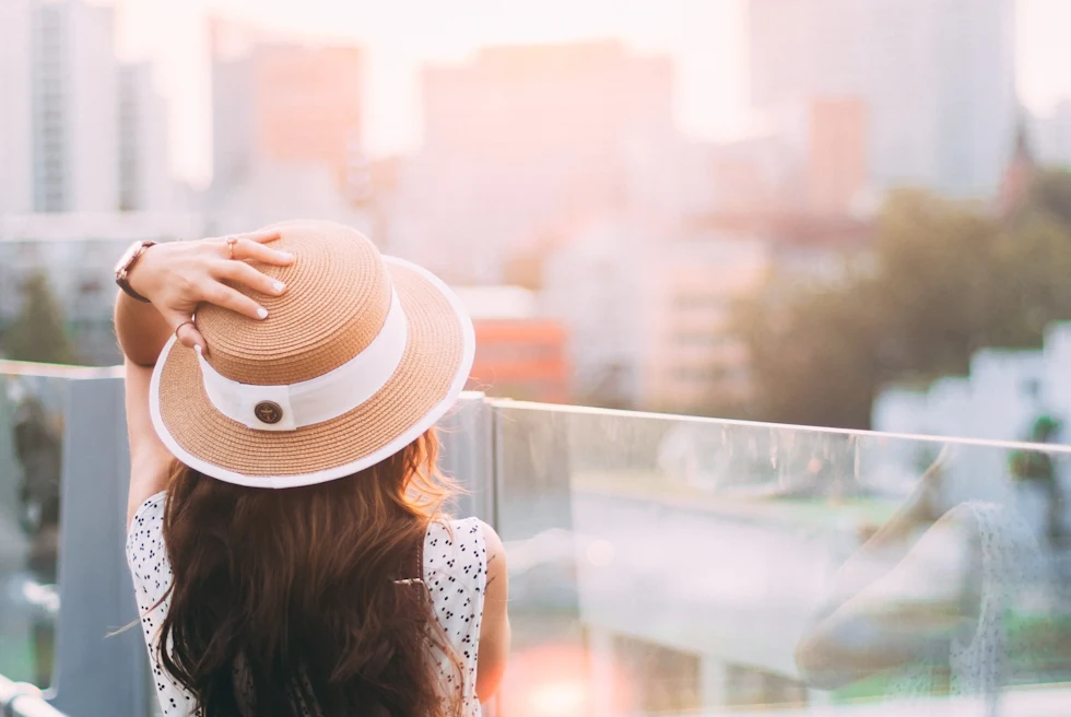 Woman in White and Black Floral Long Sleeve Shirt Wearing Brown Fedora Hat
