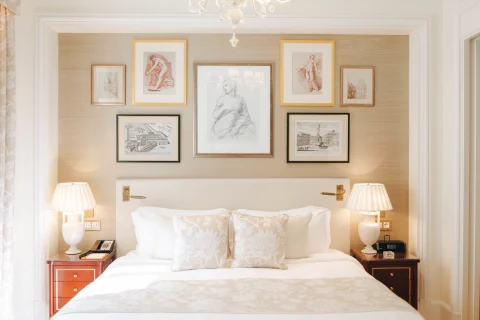 A hotel room with a white bed and artwork on the walls 