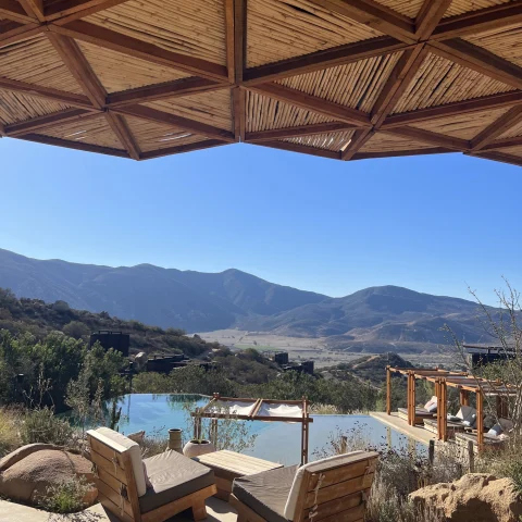 a pool of a resort hotel in a valley overlooking mountains on a clear blue day