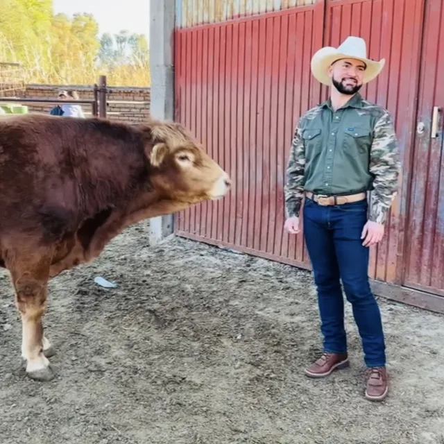 Travel advisor Christopher Anderson in cowboy hat next to a cow