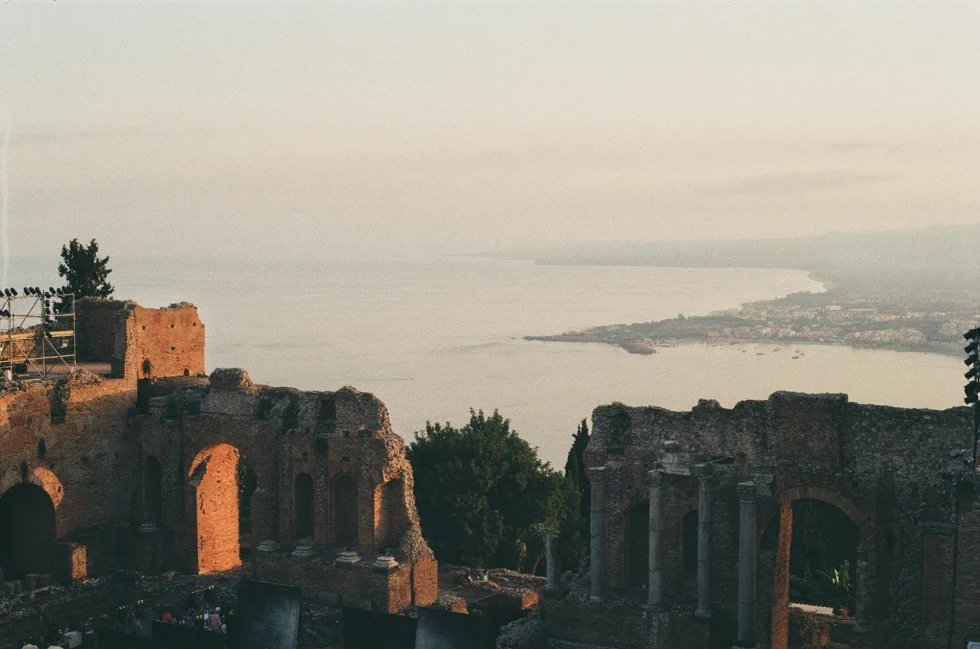 ancient roman theater remains over ocean views of a coastal city on a hazy day