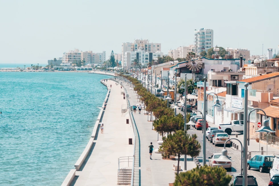 A blue sea on one side and city buildings on the other. 