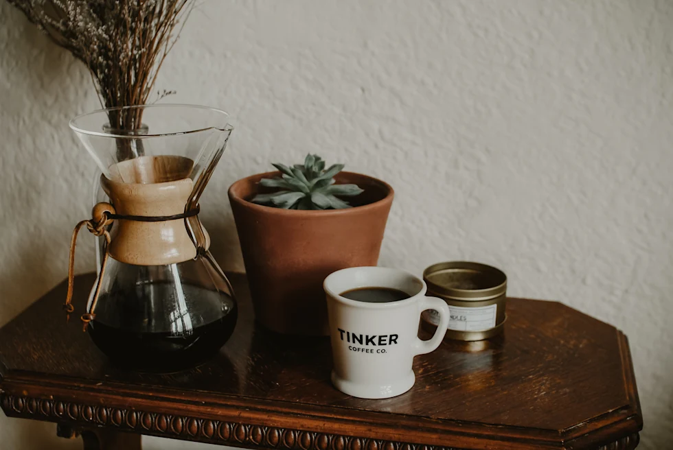 coffee cup on table next to coffee pot