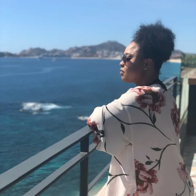 Travel Advisor Briana Medearis in a floral white top looking out to the ocean.