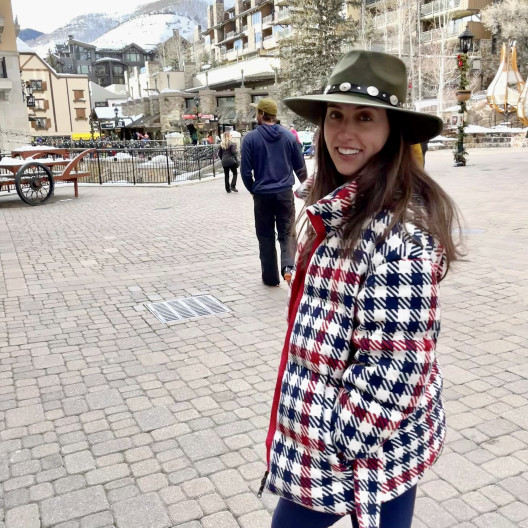 Fora Travel Agent Isabella Meyer wearing black and white jacket with buildings and mountains in the background