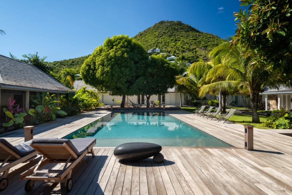 loungers by a pool on a wooden deck in the tropics