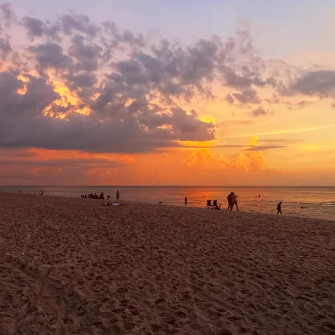 Sunset on the beach with people enjoying the view