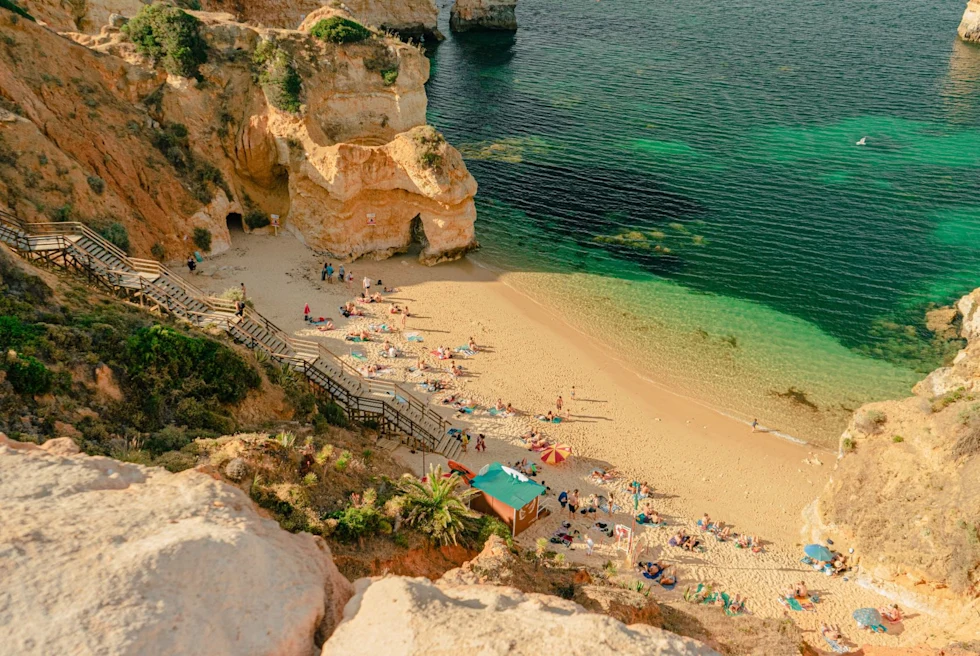 stairs on the cliff leading down to a beach cove with turquoise waters