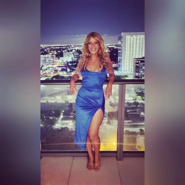 Trave advisor Alana D'Andrade posing on a balcony in a high slit blue dress.