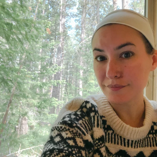 Travel Advisor Heather Sonnier in a black and white sweater with trees outside the window.