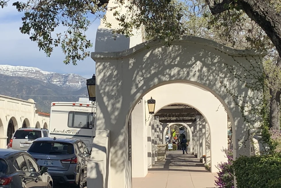 staccato archways with shadows of trees create a path through a park with mountain region in the background