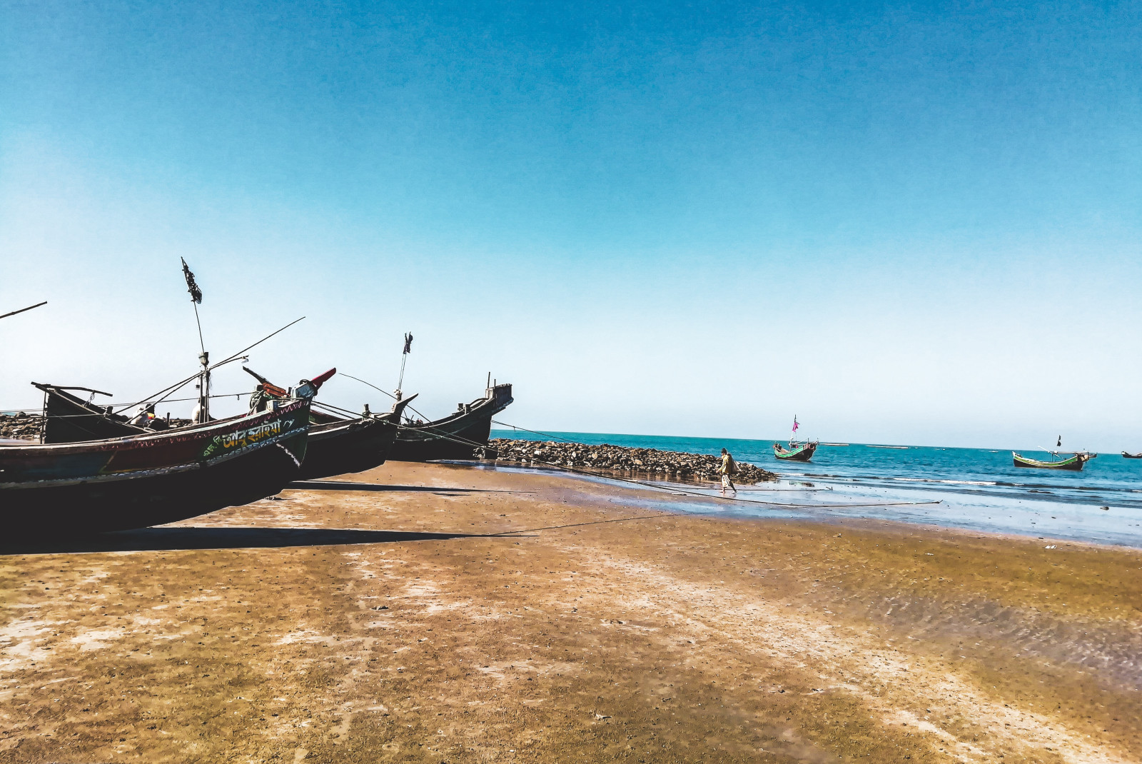 A tan sandy beach with two boats ashore and and blue water ocean in Saint Martin.