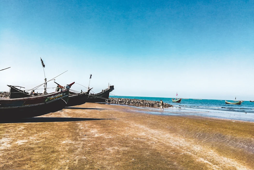 A tan sandy beach with two boats ashore and and blue water ocean in Saint Martin.