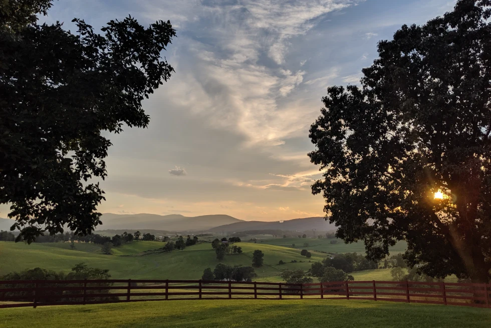 Green grass with mountains during sunset