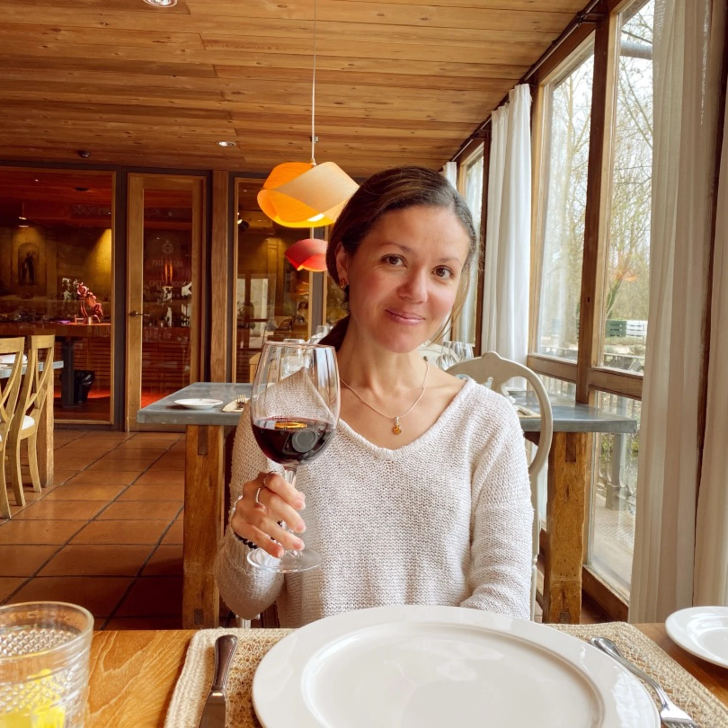 travel advisor Amalia Maloney holds up a glass of red wine in a restaurant