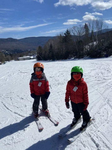 Fora Advisor Angela Poulin's twins skiing at Waterville Valley - two children in red coats on a snow-covered mountain with buildings in the background