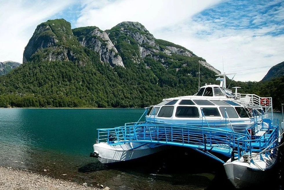 Andean crossing on lake next to mountains.