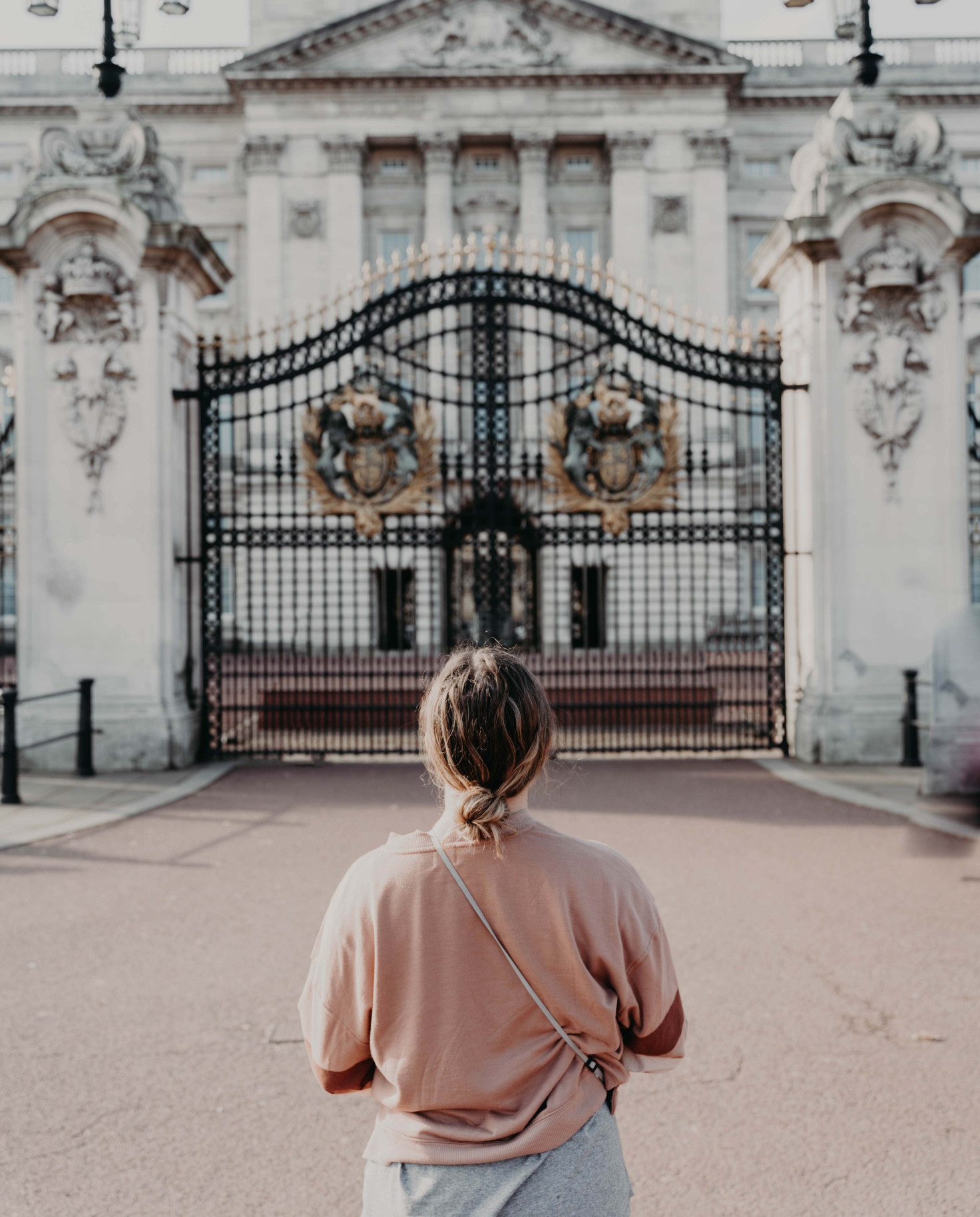 Person standing in front of large white building and black gates during daytime