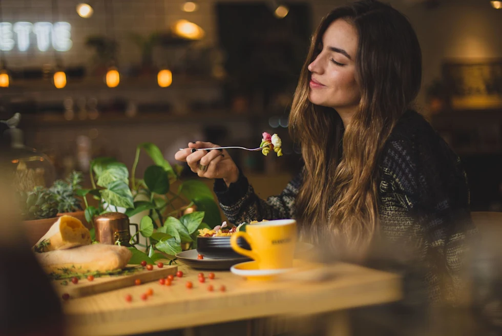 A woman holding fork with pasta.