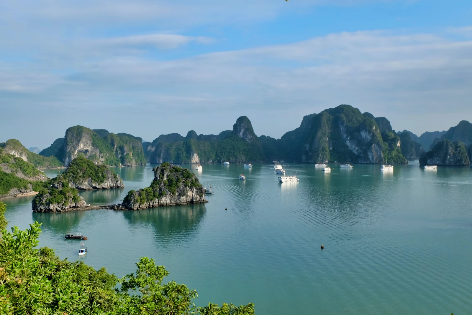Islets on an emerald bay with boats in Halong Bay. 