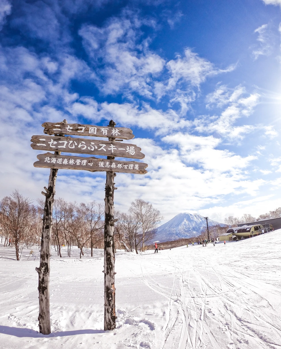 wood sign in the snow with mountain in the background during daytime