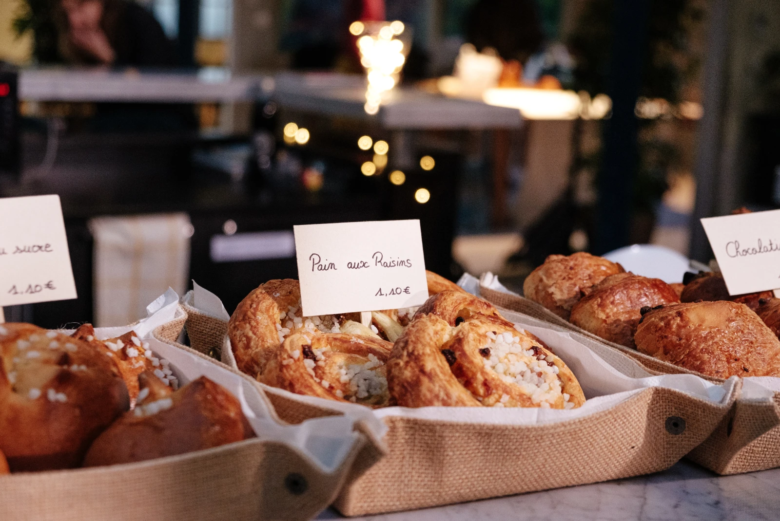 pastries with white signs and black writing in brown canvas trays in Paris France