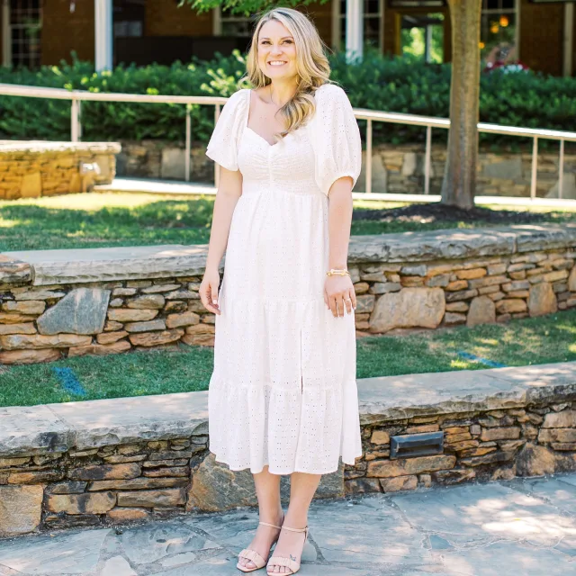 Travel Advisor Olivia Londeau in a white dress standing on grassy and stone stairs outside.