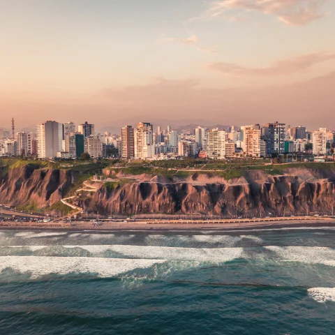 Lima, Peru city view over a cliff with ocean waves at sunset.