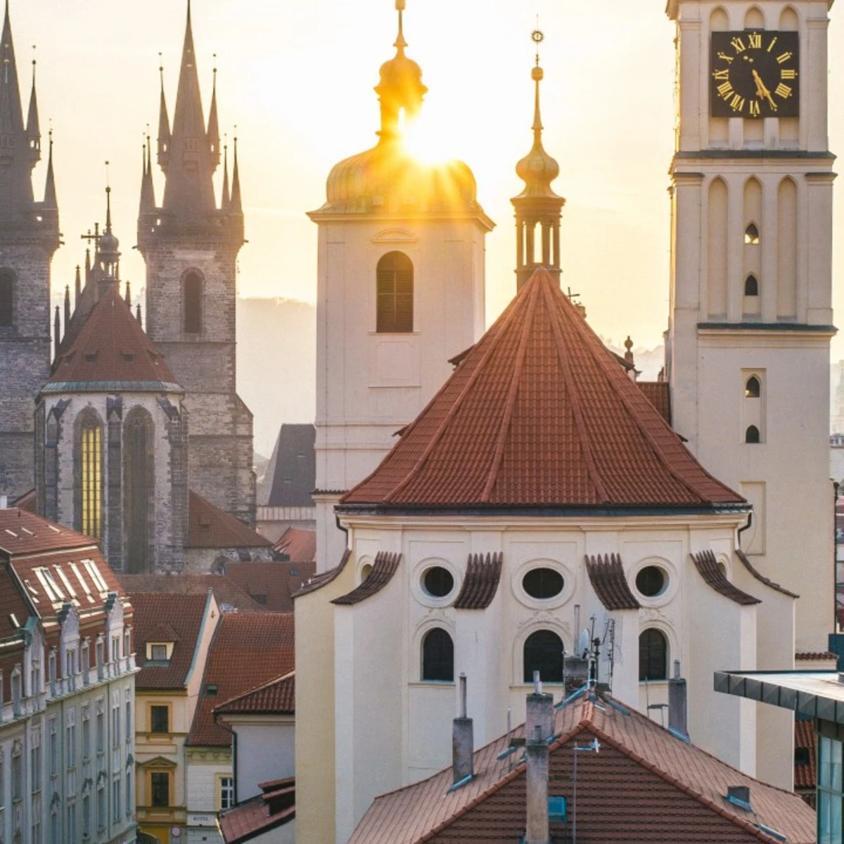 Sunset over historic buildings with brown and turquoise rooftops in Prague. 