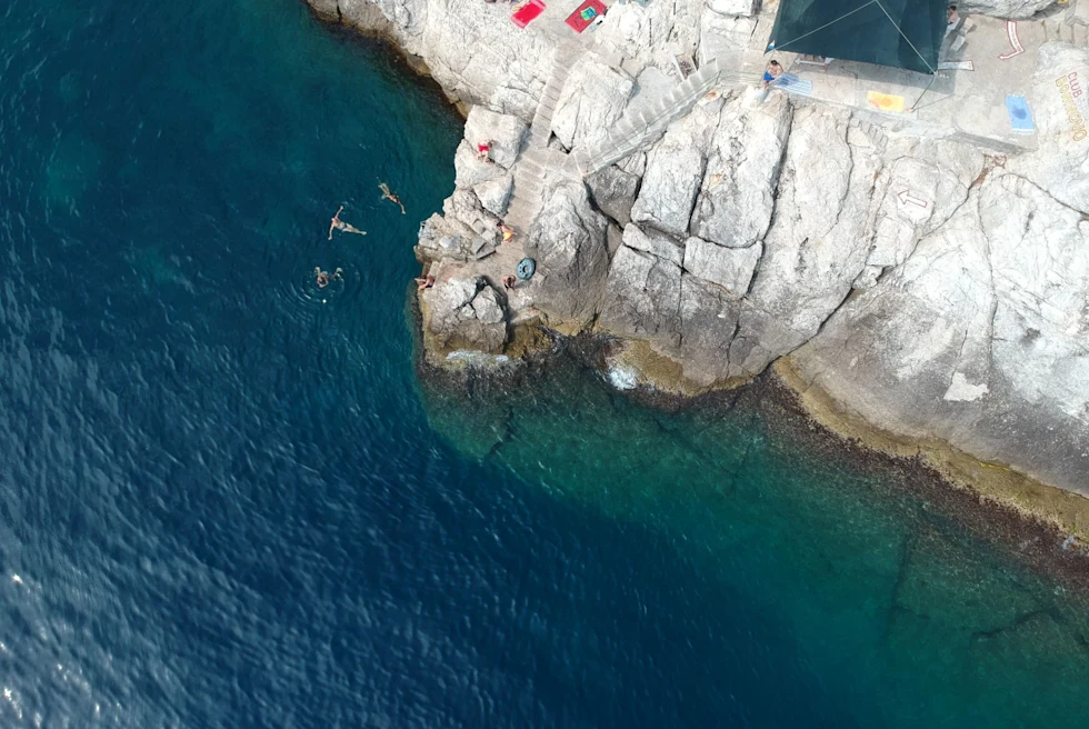 people lounge on rocky beach shore
