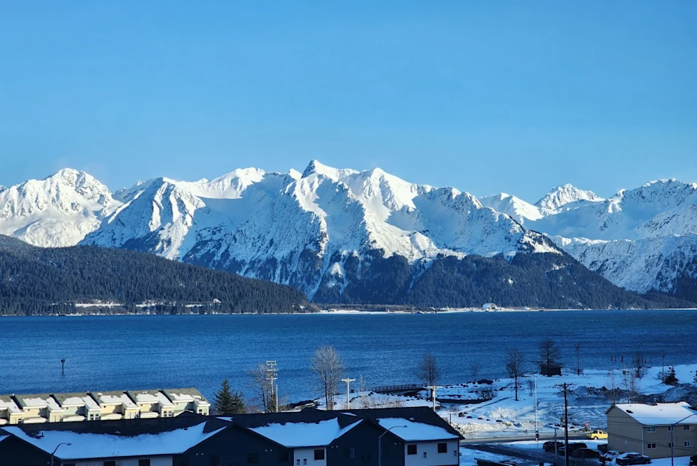 a snow-covered town near a lake and a snowy mountain