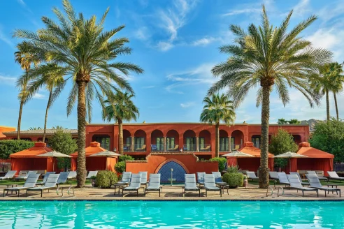 red building surrounded by palm trees and a pool
