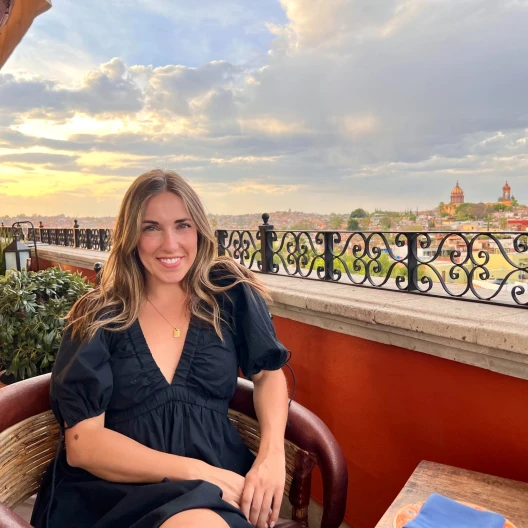 Travel Advisor Cecily Hedge smiles in a black dress on a balcony