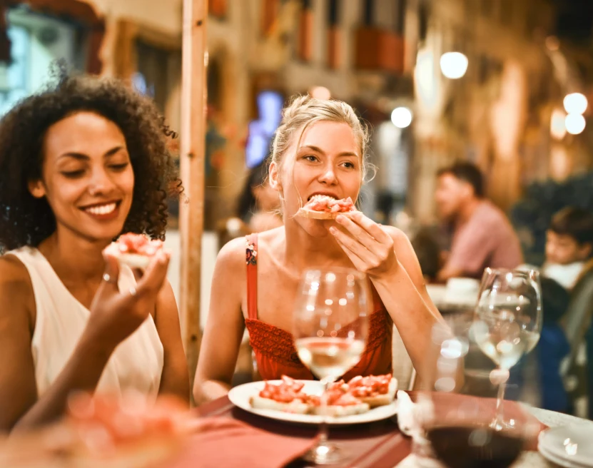 Two women enjoying a pizza and wine for dinner.