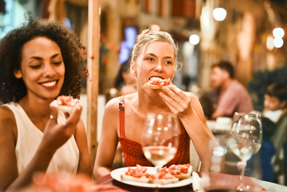 Two women enjoying a pizza and wine for dinner.