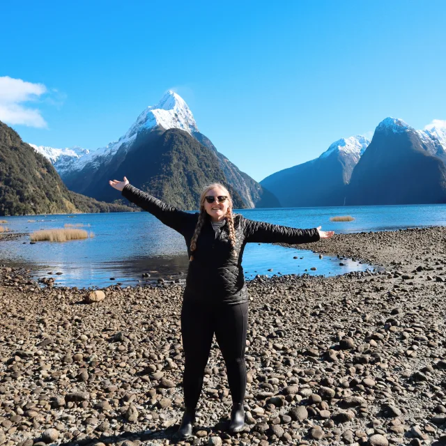 Travel Advisor Annie Decker in all black, standing in front of snowy mountains.