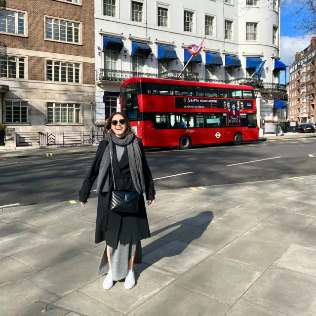 Travel Advisor Syd Wolchok is on the street with a double-decker red bus on the background.