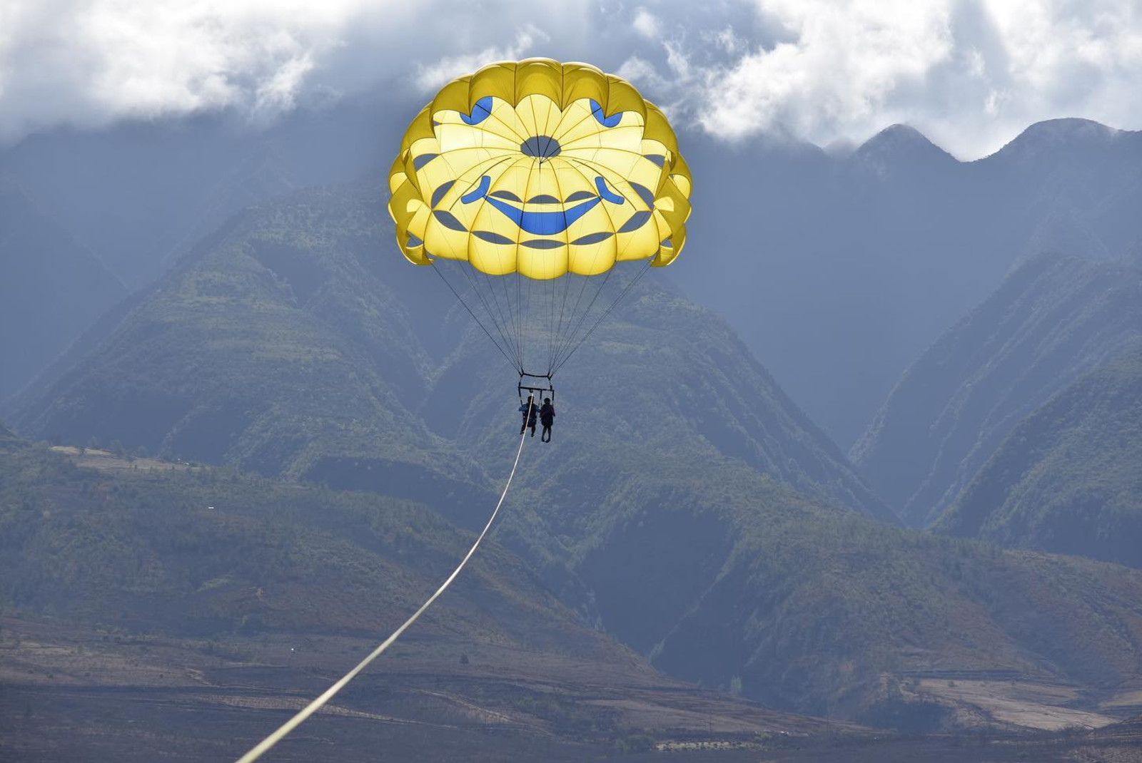 two people parasailing with mountains in the background