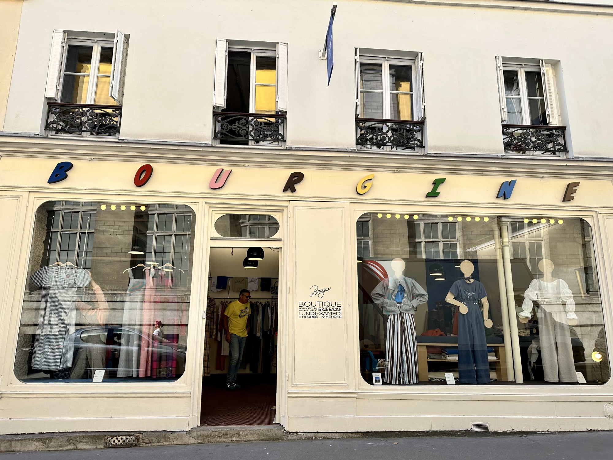 A boutique with clothes on display at the windows.