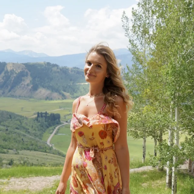 Travel Advisor Emma Cramer with a yellow floral dress and a green valley behind her.