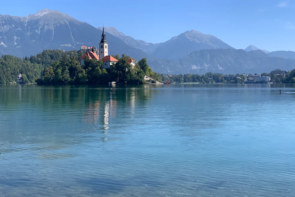 Body of water next to a building with mountains in the background during daytime