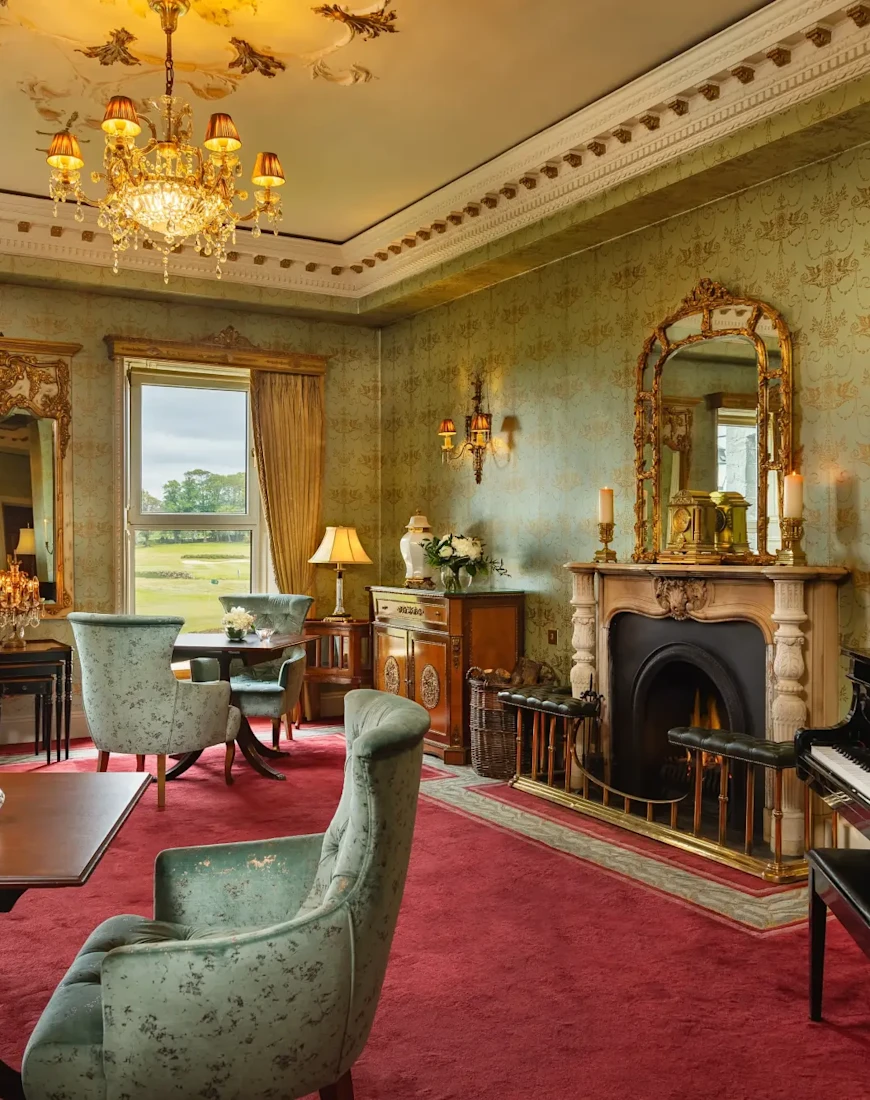 an ornate living room with a fireplace, red carpet, and an opulent chendelier
