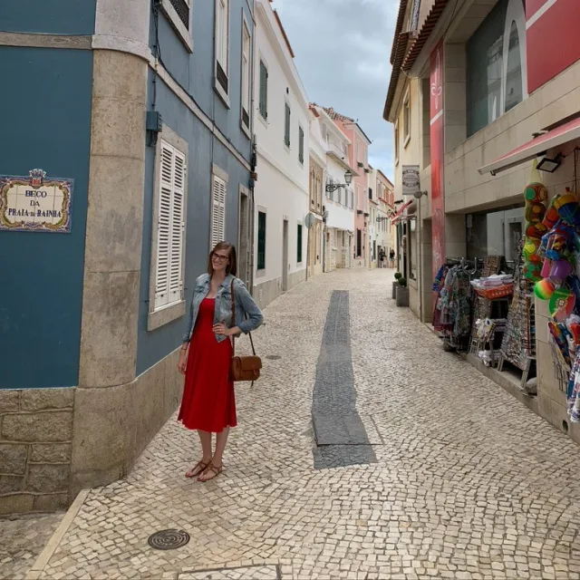 Travel Advisor Claire Rodrigues with a red dress standing on a cobblestone street.