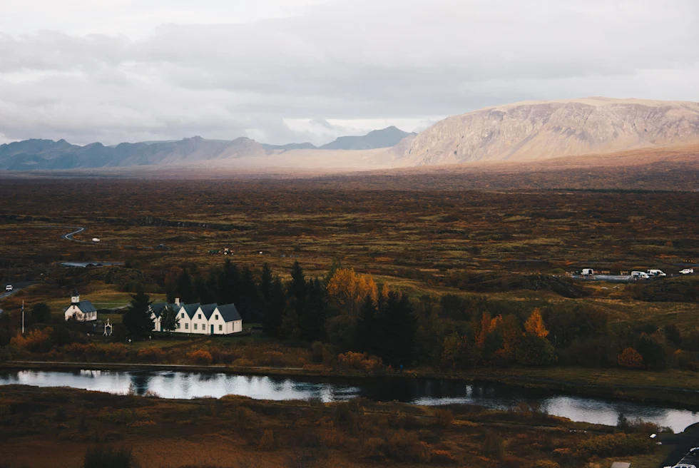 Expansive valley with two houses and clouds in the sky during daytime