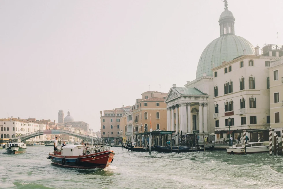 Red Boat on Body of Water Near White Concrete Building